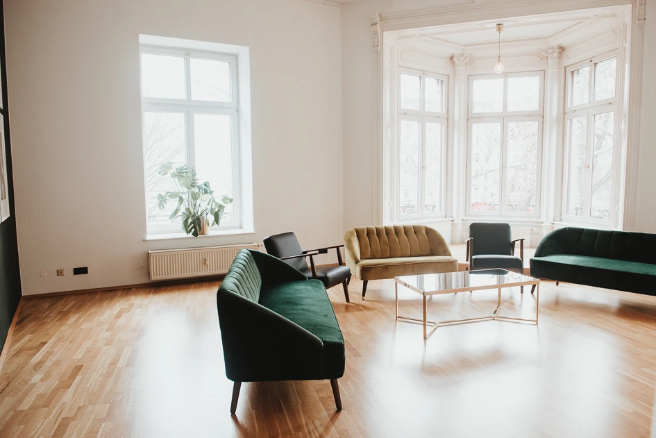 Erker mit grünen und goldenen Samtsofas und einem Glastisch
